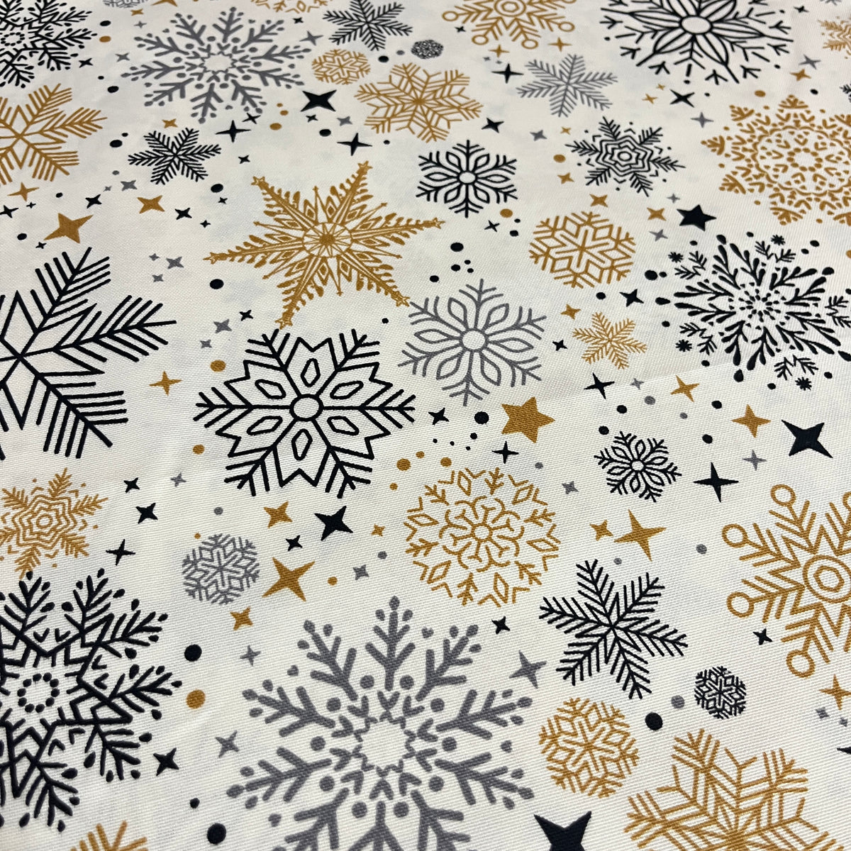 Toile déperlante de Noël flocons or et noir sur fond blanc, gros plan sur les flocons dorés et noirs - MyTissus