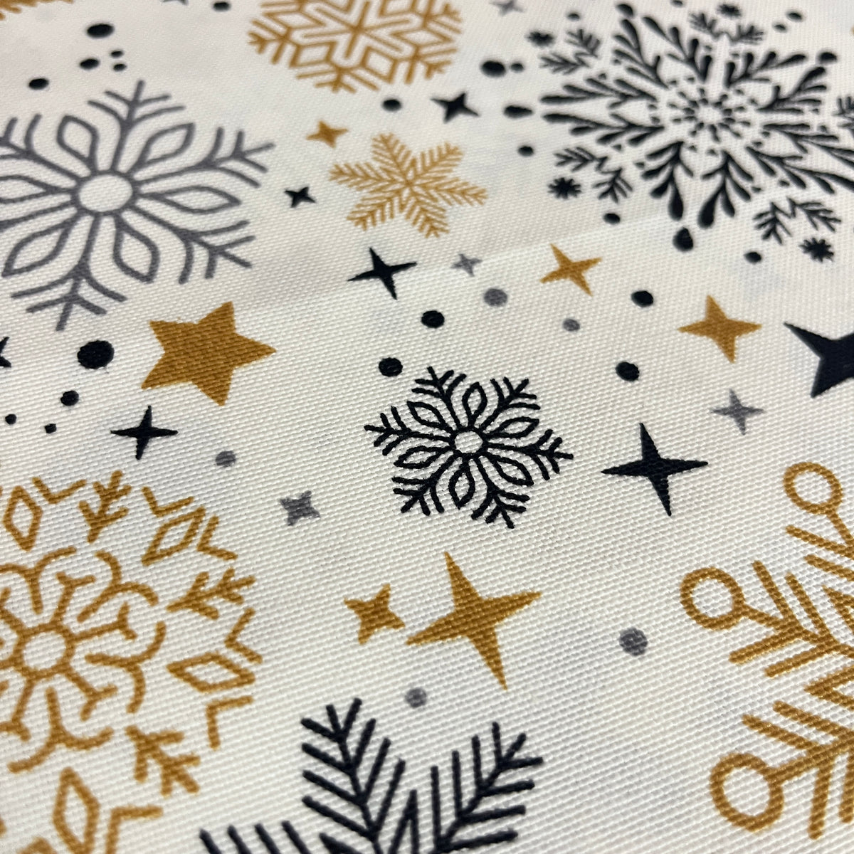 Toile déperlante de Noël flocons or et noir sur fond blanc, tissu au mètre plié - MyTissus